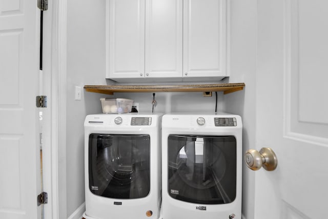 clothes washing area with separate washer and dryer and cabinet space