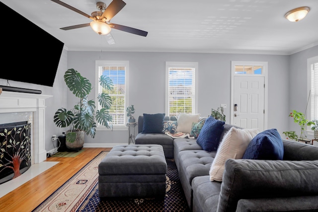 living area with ceiling fan, a high end fireplace, crown molding, wood finished floors, and baseboards