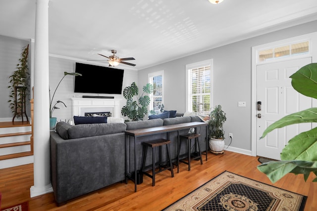 living room featuring baseboards, a fireplace, a ceiling fan, and wood finished floors