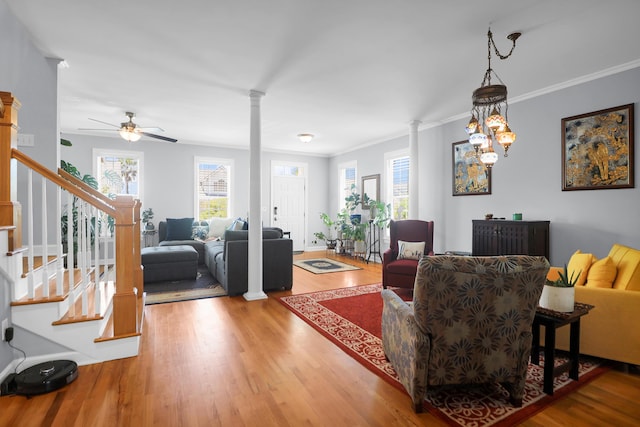 living room with light wood-style floors, decorative columns, and crown molding