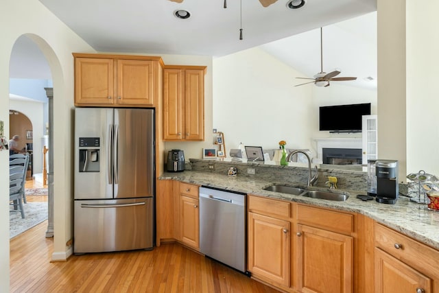 kitchen with light stone counters, a ceiling fan, appliances with stainless steel finishes, and a sink