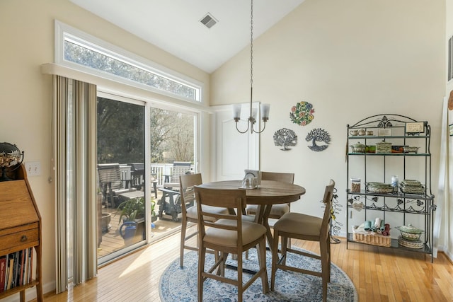 dining room featuring light wood-style flooring, a notable chandelier, visible vents, and high vaulted ceiling