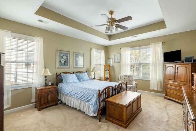 bedroom featuring visible vents, a raised ceiling, and light carpet