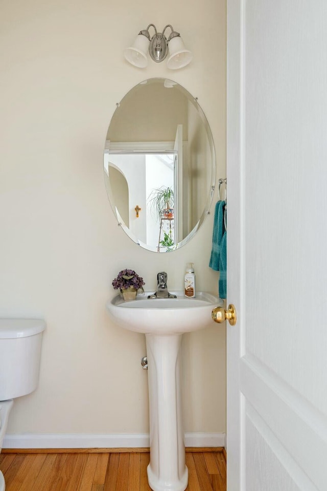 bathroom with toilet, baseboards, and wood finished floors