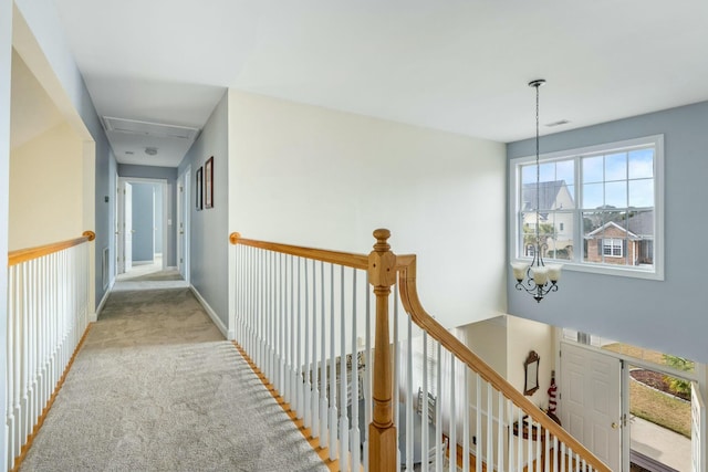 hall with baseboards, a notable chandelier, an upstairs landing, and carpet flooring