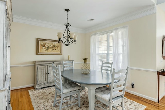 dining area featuring crown molding, light wood-style floors, and a chandelier