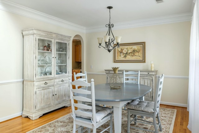 dining room featuring baseboards, light wood-style floors, arched walkways, and a chandelier