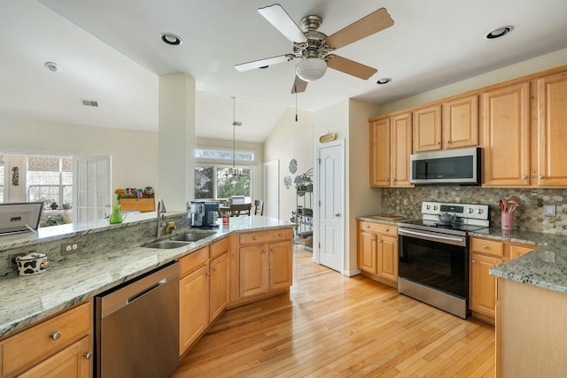 kitchen with tasteful backsplash, light wood finished floors, light stone counters, stainless steel appliances, and a sink