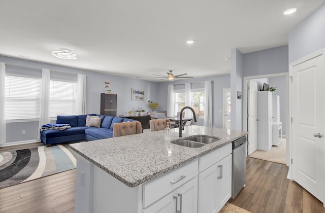 kitchen featuring a sink, white cabinets, open floor plan, dishwasher, and dark wood finished floors