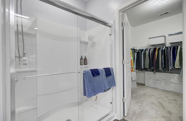 bathroom with a stall shower, a spacious closet, and visible vents