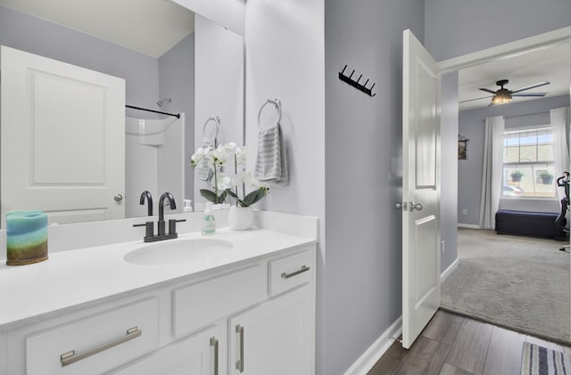 full bathroom with baseboards, wood finished floors, a ceiling fan, and vanity