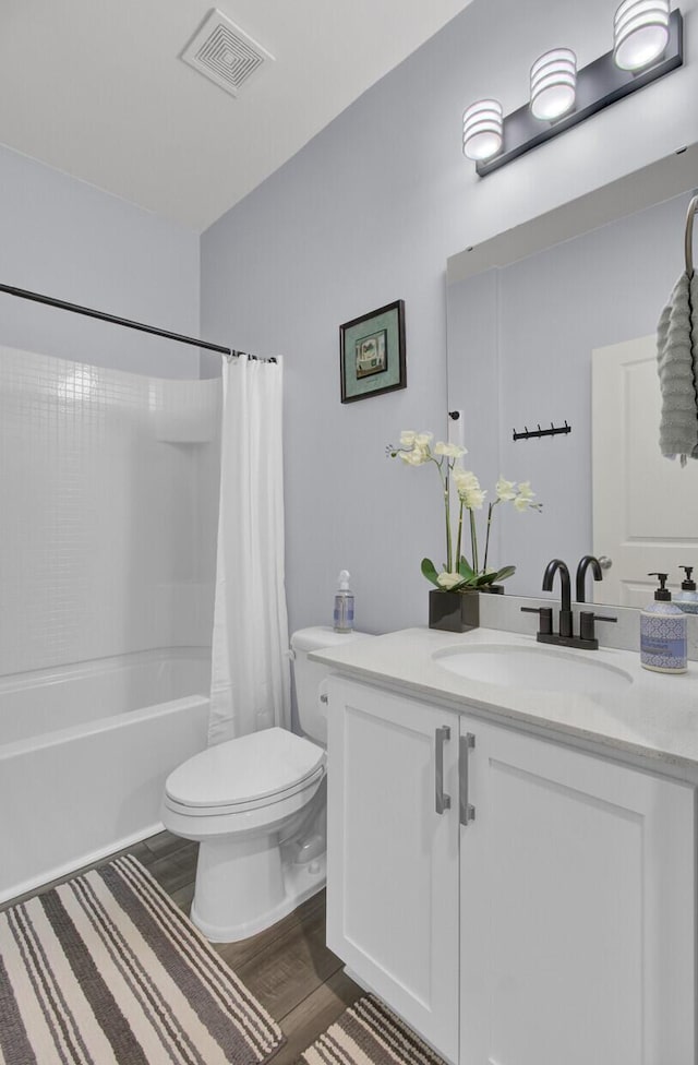 bathroom with visible vents, toilet, shower / bath combo, vanity, and wood finished floors