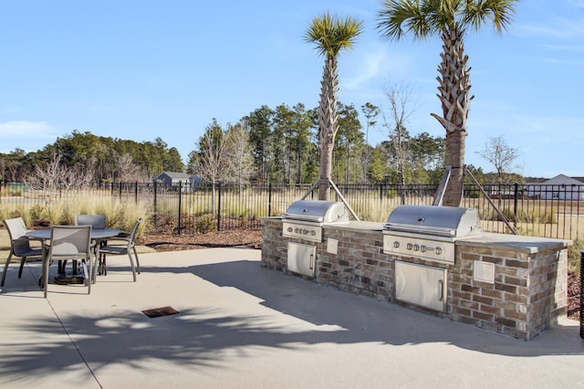 view of patio with an outdoor kitchen, outdoor dining area, fence, and grilling area