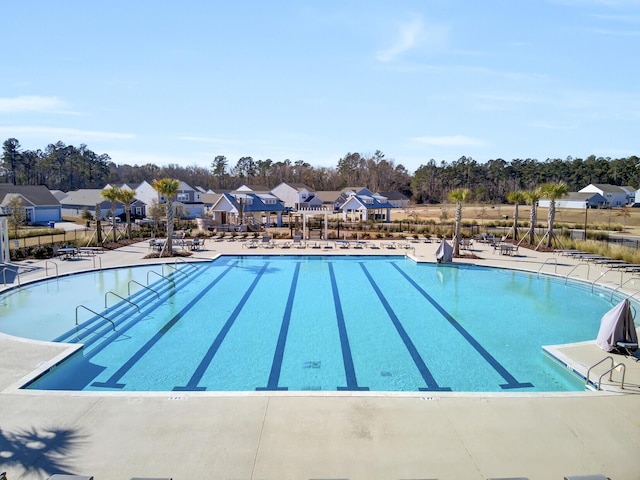 community pool with a patio, fence, and a residential view