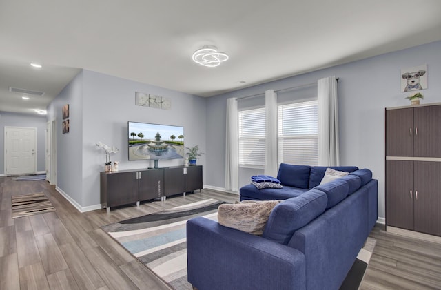 living area with wood finished floors, visible vents, and baseboards