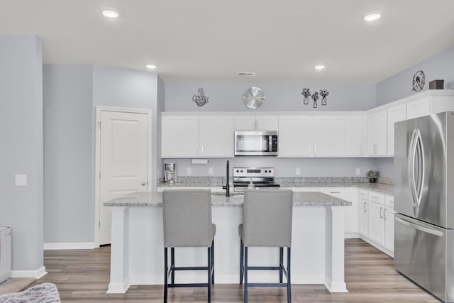 kitchen featuring an island with sink, visible vents, white cabinetry, and stainless steel appliances