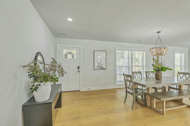 dining area with light hardwood / wood-style flooring and a chandelier