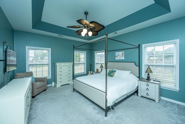 bedroom with ceiling fan, a raised ceiling, and light colored carpet