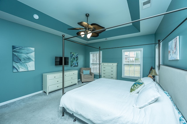 carpeted bedroom with a tray ceiling and ceiling fan