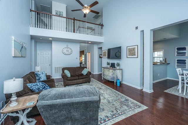 living room with a high ceiling, ceiling fan, and dark hardwood / wood-style flooring