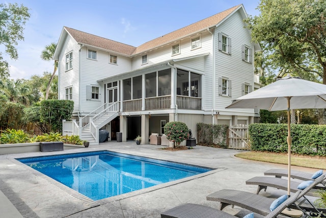 back of property with a patio, a fenced in pool, and a sunroom