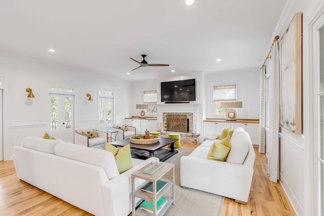 living room featuring a fireplace, ceiling fan, light hardwood / wood-style flooring, and french doors