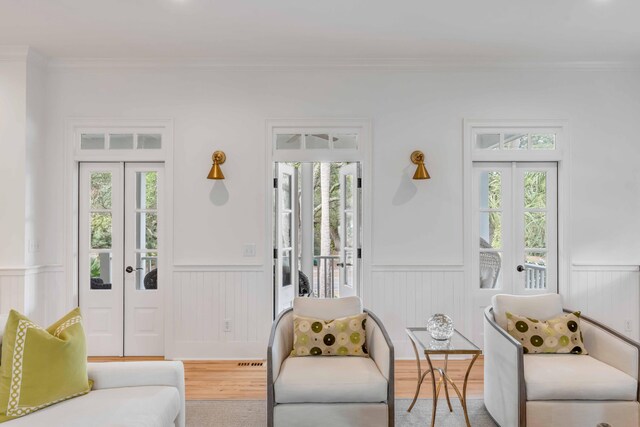 living room with hardwood / wood-style flooring, plenty of natural light, ornamental molding, and french doors