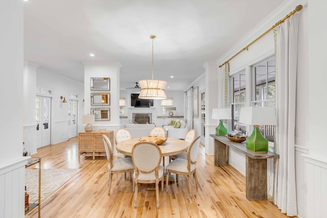 dining space featuring light wood-type flooring, ornamental molding, and french doors