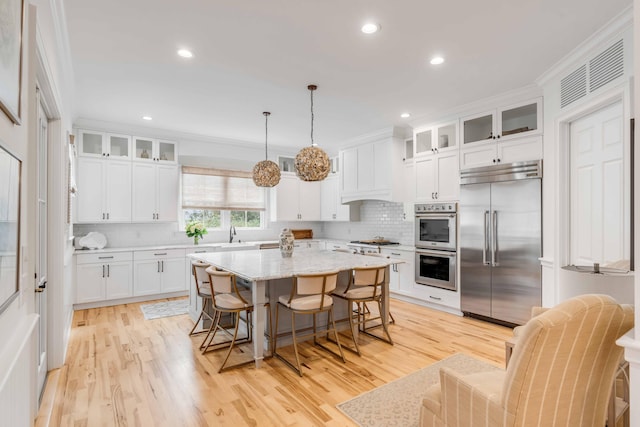 kitchen featuring a center island, ornamental molding, hanging light fixtures, and appliances with stainless steel finishes