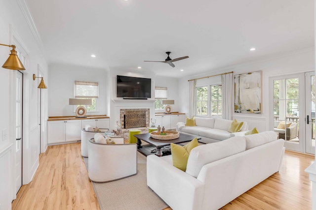 living room with ceiling fan, light wood-type flooring, and ornamental molding