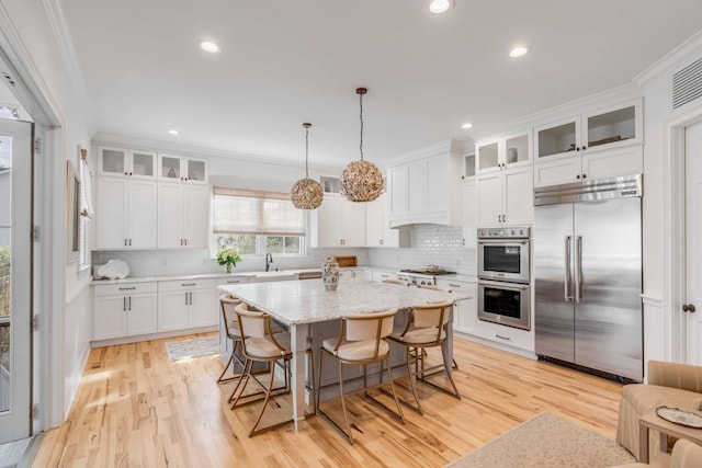 kitchen featuring white cabinetry, a center island, decorative light fixtures, and appliances with stainless steel finishes