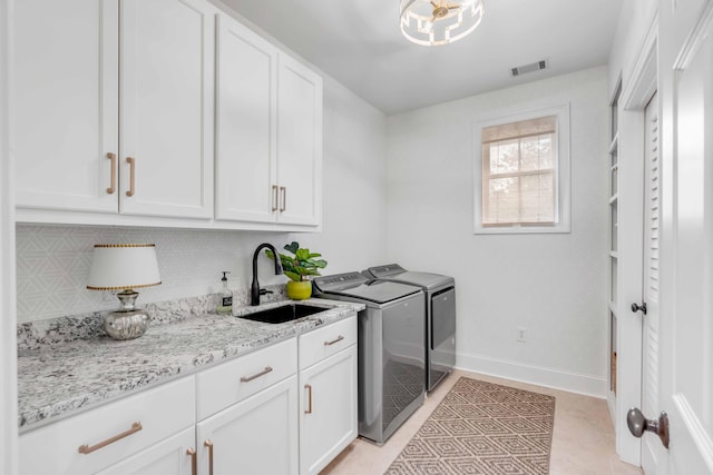 clothes washing area featuring cabinets, sink, light tile patterned flooring, and washer and dryer