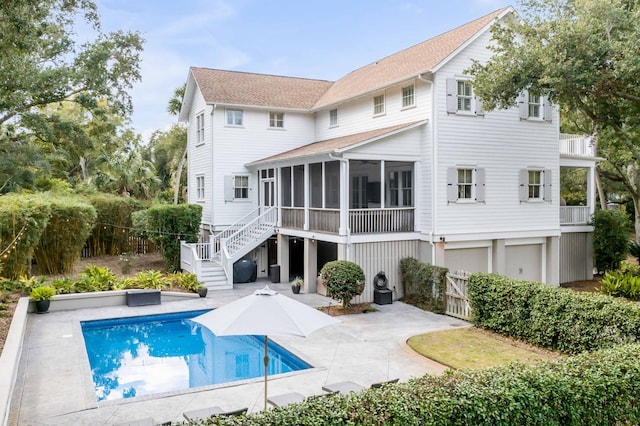 rear view of house with a fenced in pool, a patio area, and a sunroom