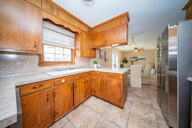 kitchen with stainless steel refrigerator, a healthy amount of sunlight, kitchen peninsula, and sink