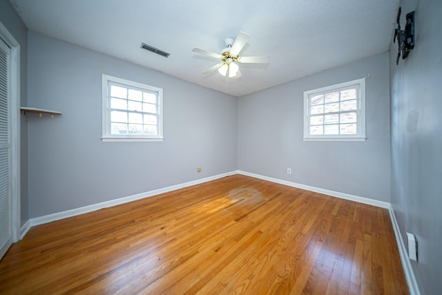 empty room featuring wood-type flooring, plenty of natural light, and ceiling fan