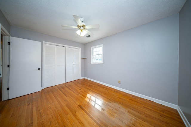 unfurnished bedroom featuring ceiling fan, wood-type flooring, a closet, and a textured ceiling