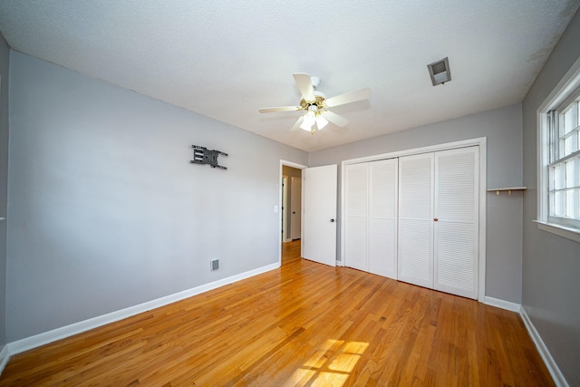 unfurnished bedroom with a textured ceiling, light hardwood / wood-style floors, a closet, and ceiling fan