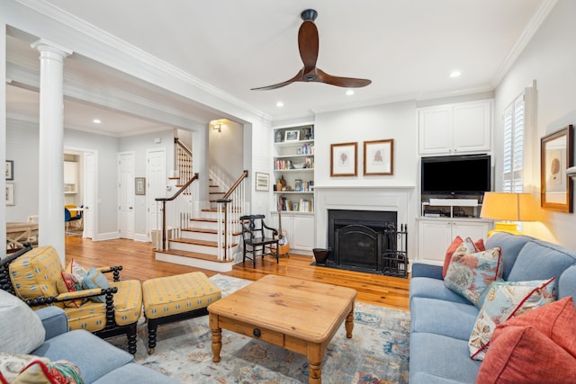 living room with built in shelves, ornate columns, crown molding, light hardwood / wood-style flooring, and ceiling fan