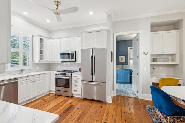 kitchen featuring light stone counters, stainless steel appliances, light hardwood / wood-style floors, and white cabinets