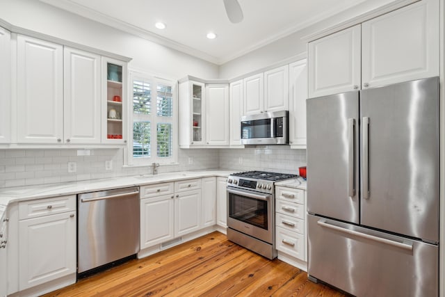 kitchen featuring white cabinetry, stainless steel appliances, crown molding, and decorative backsplash