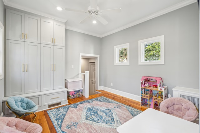 recreation room with crown molding, ceiling fan, and light hardwood / wood-style floors