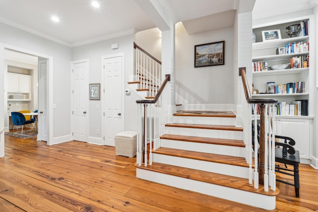 staircase featuring ornamental molding and hardwood / wood-style floors