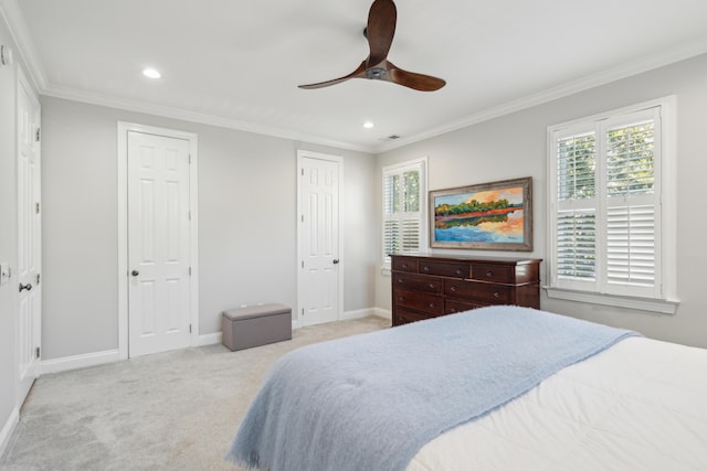 bedroom featuring light carpet, two closets, ornamental molding, and ceiling fan