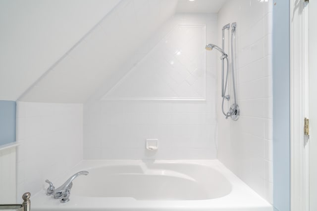 bathroom featuring lofted ceiling and a bath