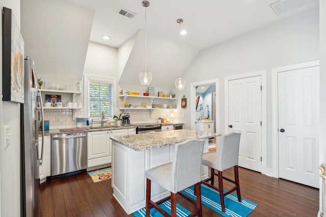 kitchen featuring a kitchen bar, white cabinetry, a center island, appliances with stainless steel finishes, and pendant lighting