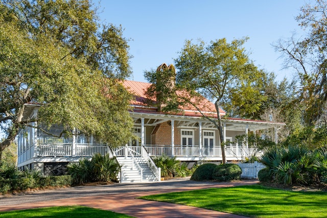 farmhouse inspired home with french doors, covered porch, and a front lawn