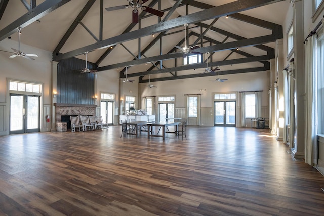 unfurnished living room featuring dark wood-type flooring, french doors, a brick fireplace, ceiling fan, and beam ceiling