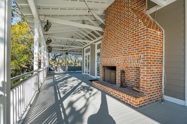 wooden terrace featuring an outdoor brick fireplace