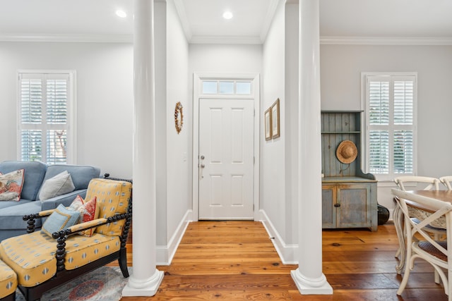 foyer entrance with hardwood / wood-style flooring, crown molding, and ornate columns