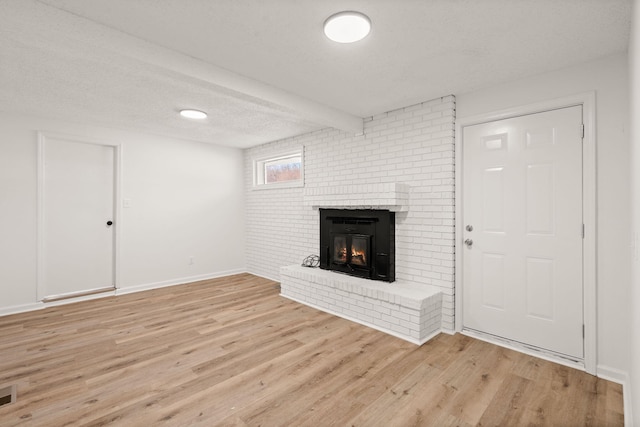 unfurnished living room with a fireplace, light wood-type flooring, and a textured ceiling